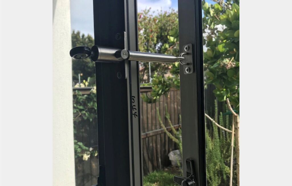 Locklatch installed in metal patio door with garden in the background